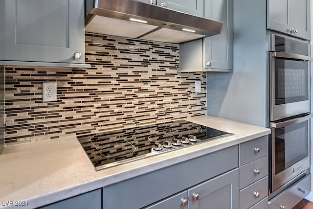 kitchen with gray cabinets, double oven, and tasteful backsplash