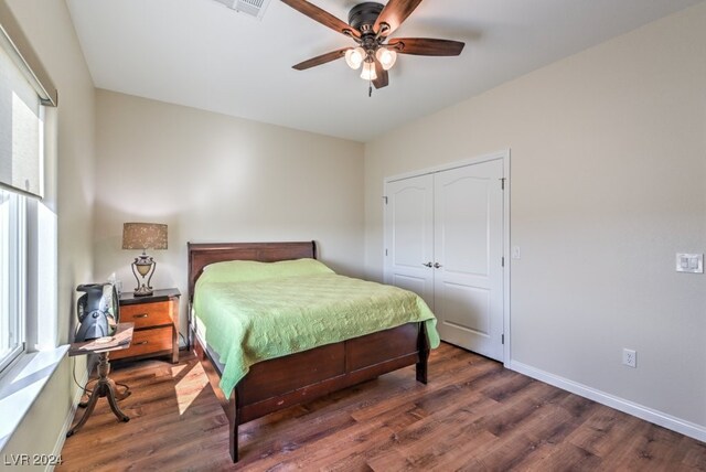 bedroom featuring multiple windows, ceiling fan, a closet, and dark hardwood / wood-style floors