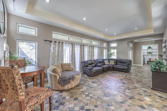 living area with a raised ceiling, arched walkways, baseboards, and recessed lighting