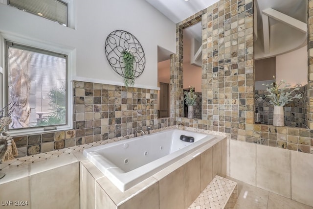 full bathroom with a whirlpool tub, tile walls, and decorative columns