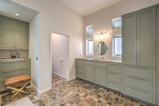 bathroom featuring stone finish flooring, vanity, and baseboards