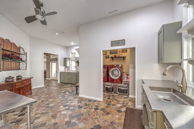 kitchen with a ceiling fan, stainless steel countertops, a sink, washer and dryer, and baseboards