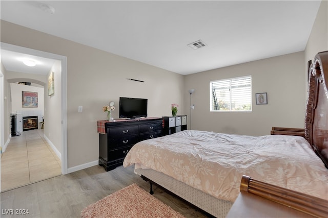 bedroom featuring wood-type flooring and a fireplace