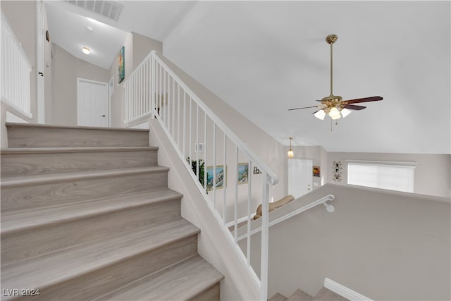 stairs with ceiling fan and high vaulted ceiling