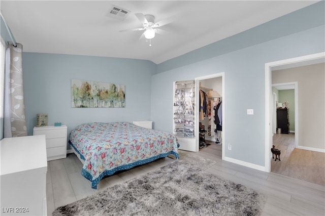 bedroom with ceiling fan, a closet, a spacious closet, light wood-type flooring, and vaulted ceiling