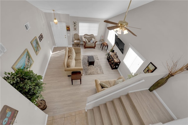 living room with light wood-type flooring, ceiling fan, and high vaulted ceiling