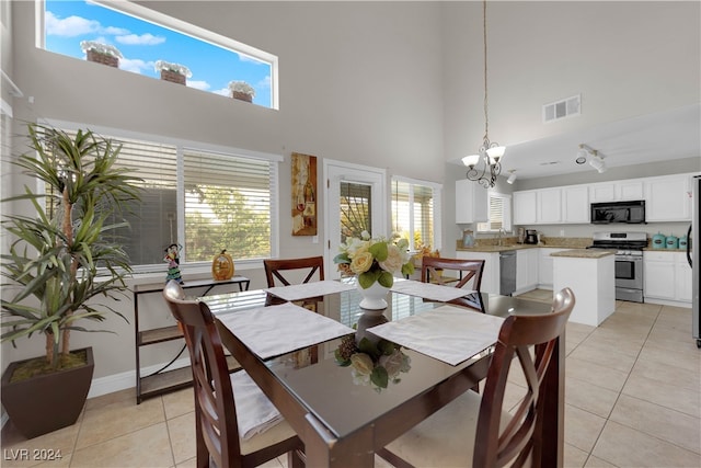 dining space with light tile patterned flooring, a towering ceiling, a chandelier, and a wealth of natural light