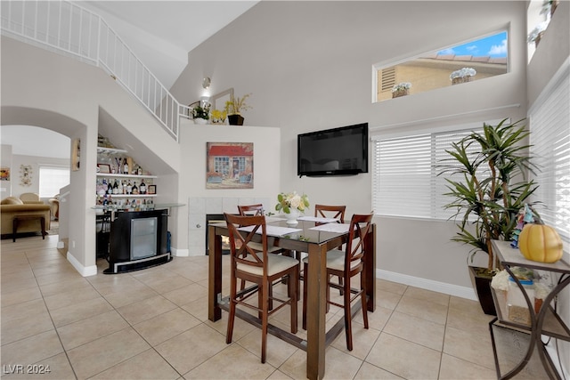 tiled dining room with high vaulted ceiling and a healthy amount of sunlight