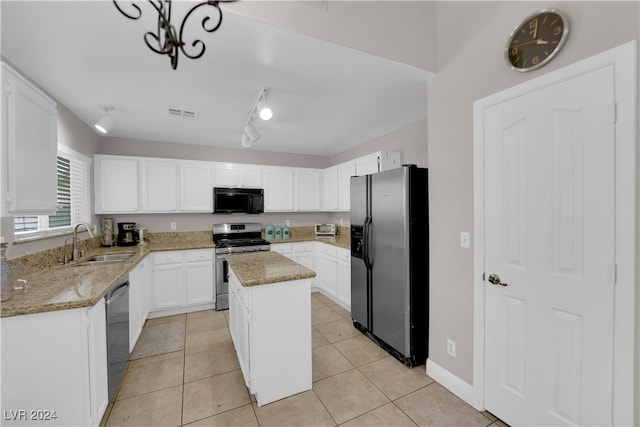 kitchen with light stone counters, white cabinets, sink, appliances with stainless steel finishes, and a center island