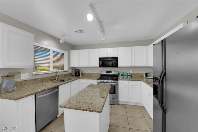 kitchen featuring appliances with stainless steel finishes, rail lighting, light stone counters, white cabinets, and a center island