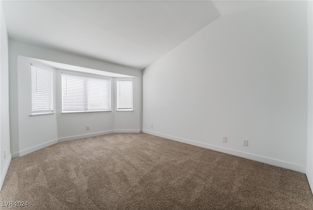 empty room with lofted ceiling and carpet flooring