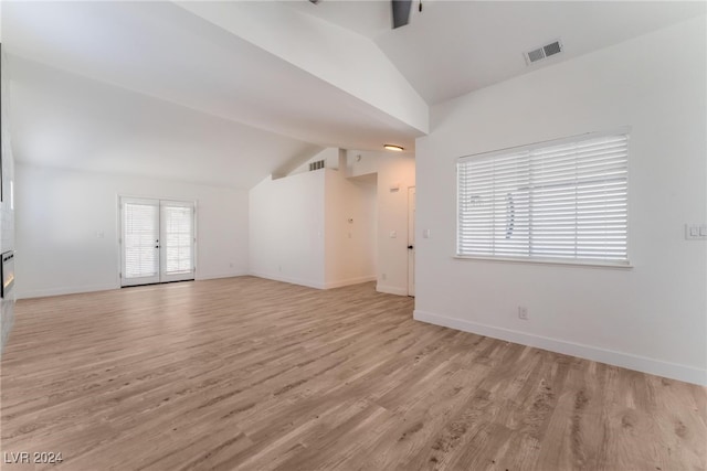 unfurnished living room with french doors, lofted ceiling, and light hardwood / wood-style floors