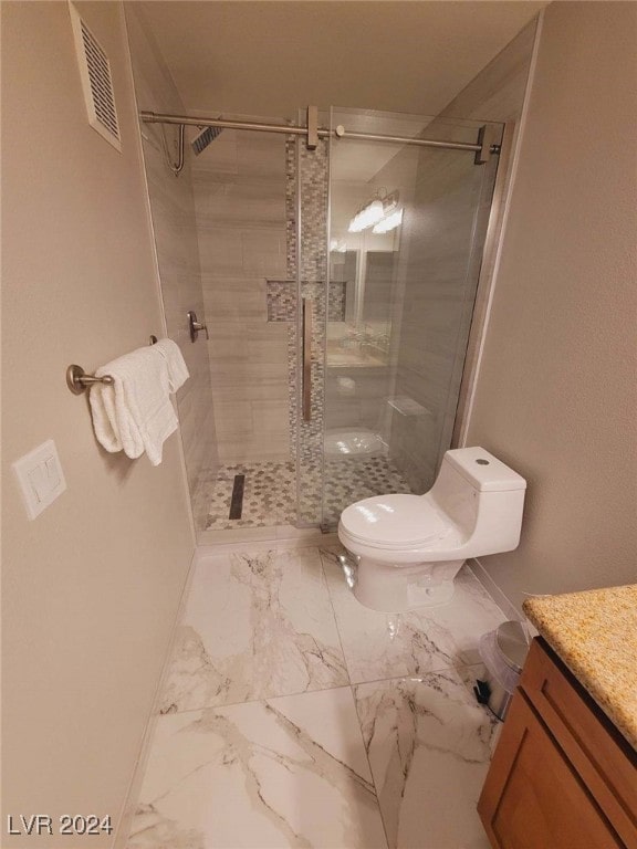 bathroom featuring vanity, a shower with shower door, and toilet