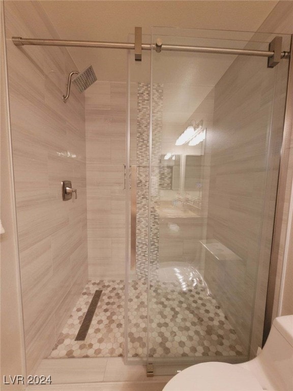 bathroom featuring a shower with shower door and toilet