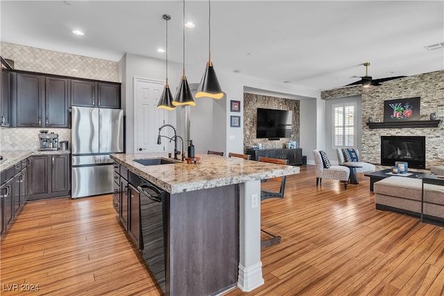 kitchen with a center island with sink, a breakfast bar area, black appliances, pendant lighting, and sink