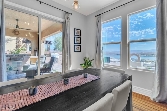 dining area featuring hardwood / wood-style flooring, ceiling fan, a water view, and a wealth of natural light