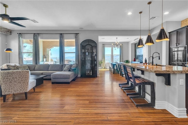 living room with sink, dark hardwood / wood-style flooring, and ceiling fan with notable chandelier