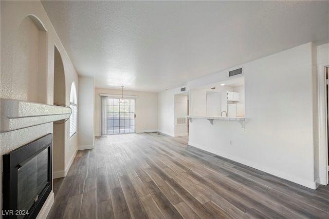 unfurnished living room featuring a textured ceiling and dark hardwood / wood-style flooring