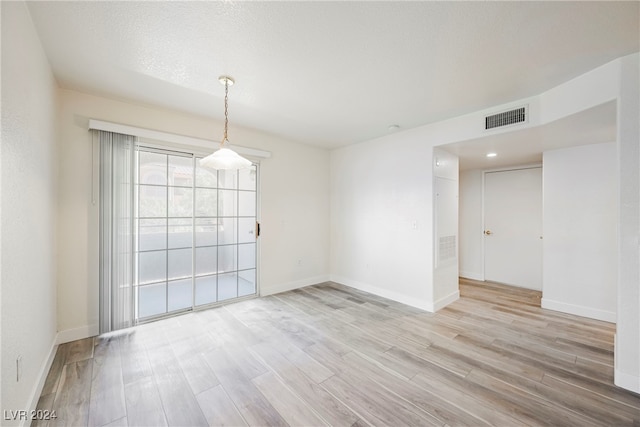 spare room with light hardwood / wood-style floors and a textured ceiling