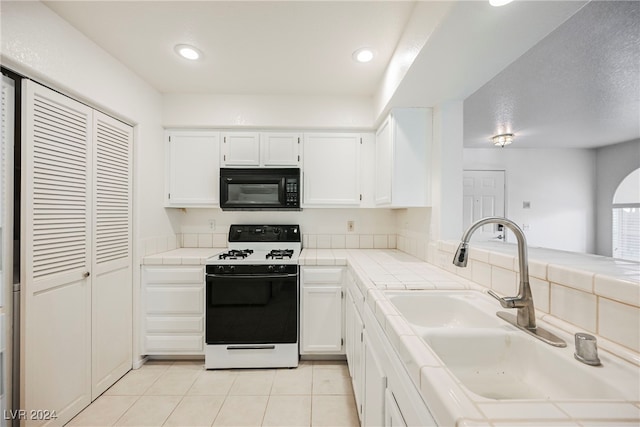 kitchen featuring white cabinetry, white stove, light tile patterned flooring, tile counters, and sink