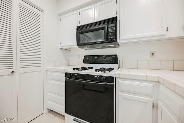 kitchen with white range with gas cooktop, tile counters, white cabinets, and light tile patterned floors