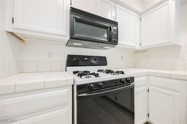 kitchen featuring white range with gas stovetop, white cabinetry, tile countertops, and tile patterned flooring