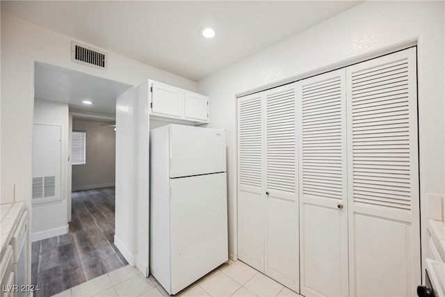 kitchen with white cabinets, light hardwood / wood-style floors, and white refrigerator