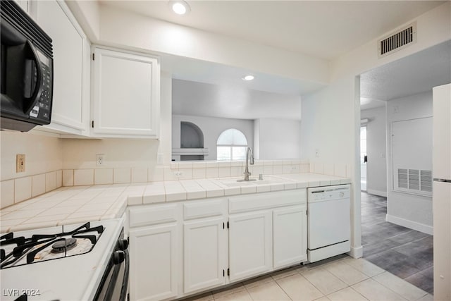 kitchen with white appliances, tile countertops, white cabinetry, and sink