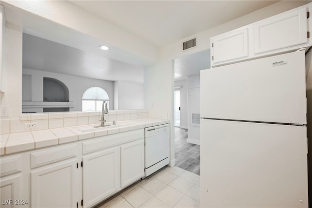 kitchen featuring tile counters, light hardwood / wood-style flooring, sink, white cabinets, and white appliances