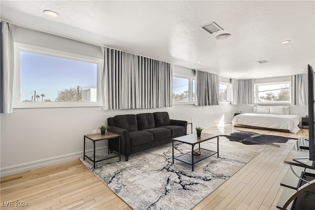 bedroom with multiple windows, a textured ceiling, and light wood-type flooring