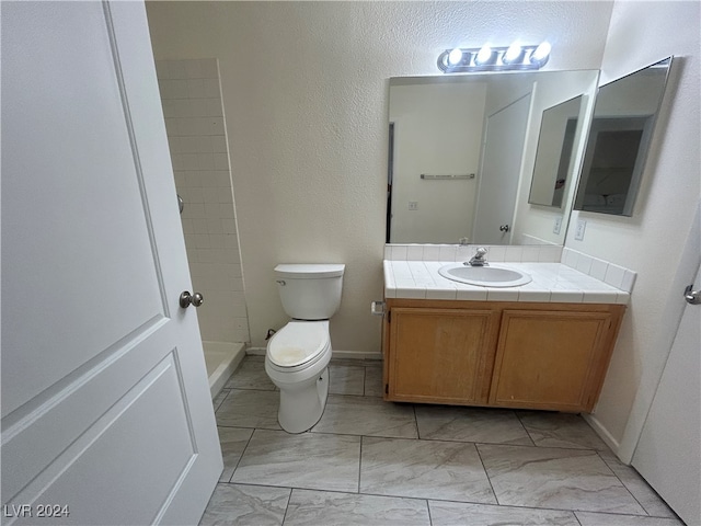 bathroom with walk in shower, vanity, and toilet