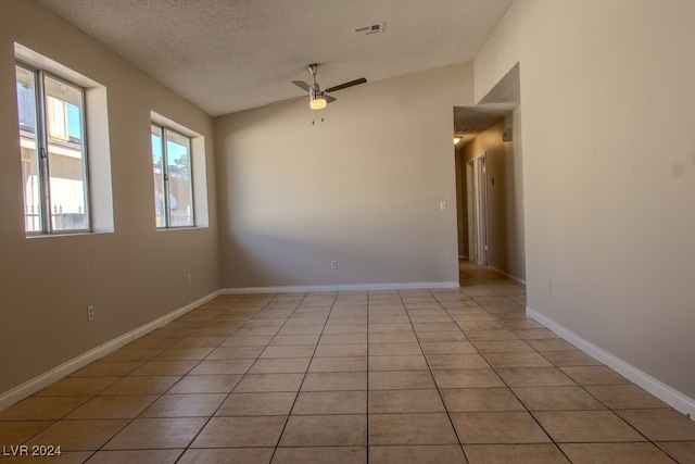 tiled empty room with a textured ceiling, ceiling fan, and lofted ceiling