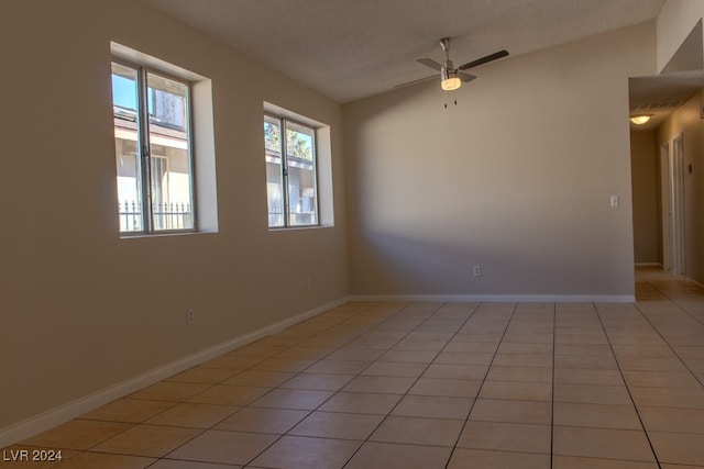 empty room featuring a textured ceiling, ceiling fan, light tile patterned floors, and lofted ceiling