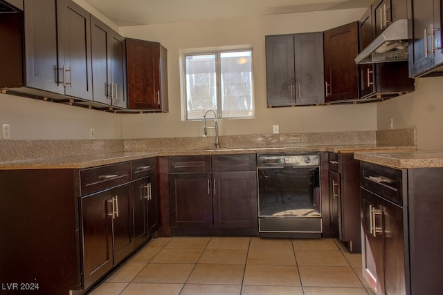 kitchen with ventilation hood, sink, light tile patterned floors, black dishwasher, and dark brown cabinetry