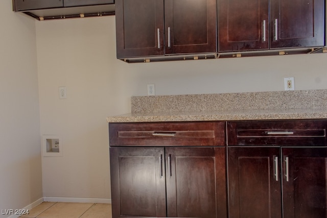 kitchen featuring dark brown cabinets, light stone countertops, and light tile patterned floors