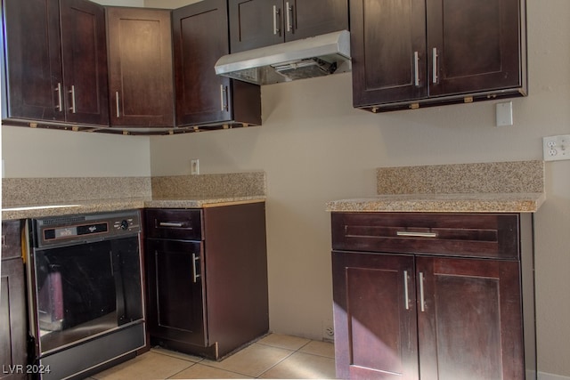 kitchen featuring dark brown cabinetry, oven, and light tile patterned floors