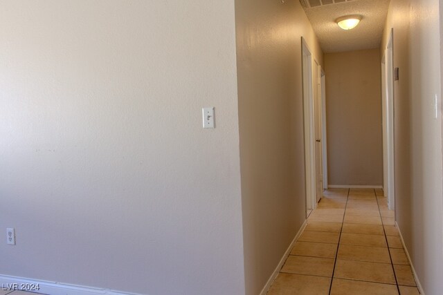 corridor featuring light tile patterned floors and a textured ceiling