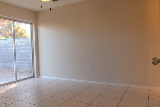 tiled empty room with ceiling fan and a textured ceiling