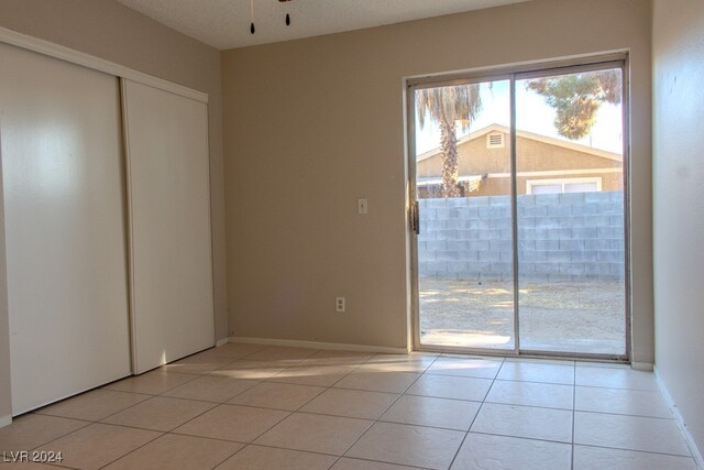 interior space featuring access to exterior, a closet, light tile patterned floors, and a textured ceiling