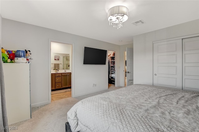 bedroom with light carpet, connected bathroom, and a spacious closet