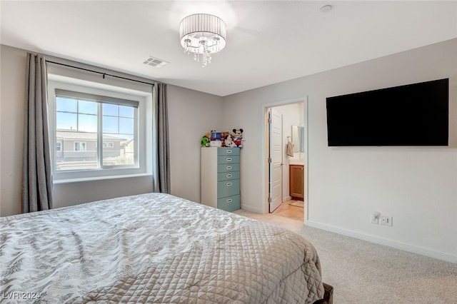 bedroom with light colored carpet, ensuite bath, and a chandelier