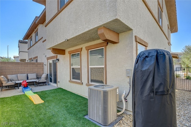 view of side of home with central AC unit, an outdoor living space, a yard, and a patio area