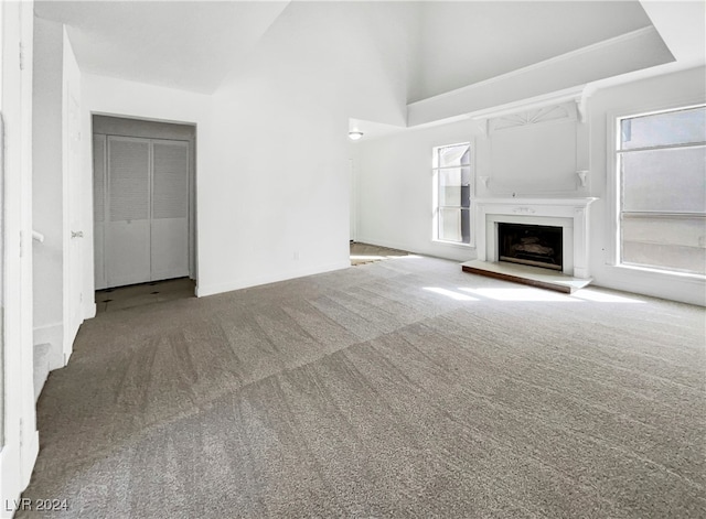 unfurnished living room featuring high vaulted ceiling and carpet