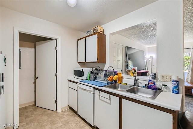 kitchen featuring white appliances, light countertops, a sink, white cabinetry, and a textured ceiling
