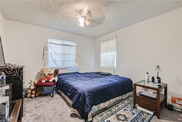 carpeted bedroom featuring ceiling fan and a textured ceiling