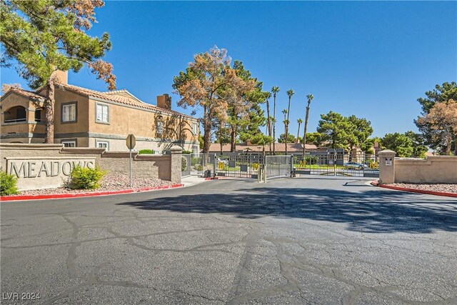 view of street featuring a gated entry, a residential view, a gate, curbs, and traffic signs