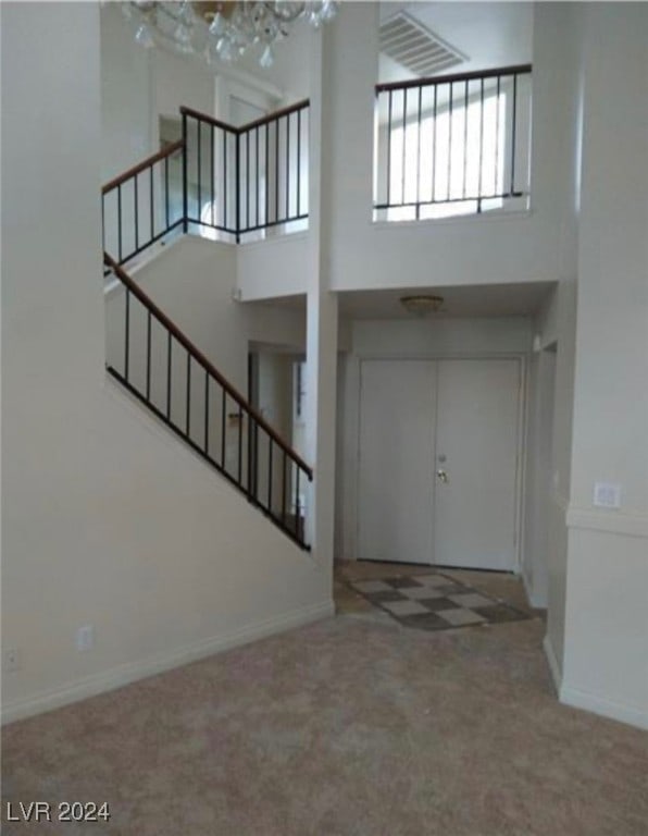 foyer with carpet floors and a notable chandelier