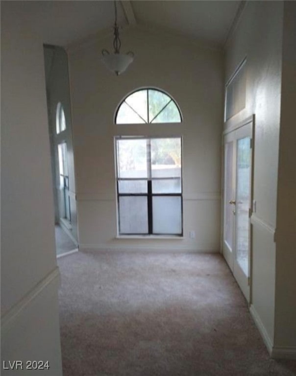 empty room featuring french doors, high vaulted ceiling, and carpet flooring