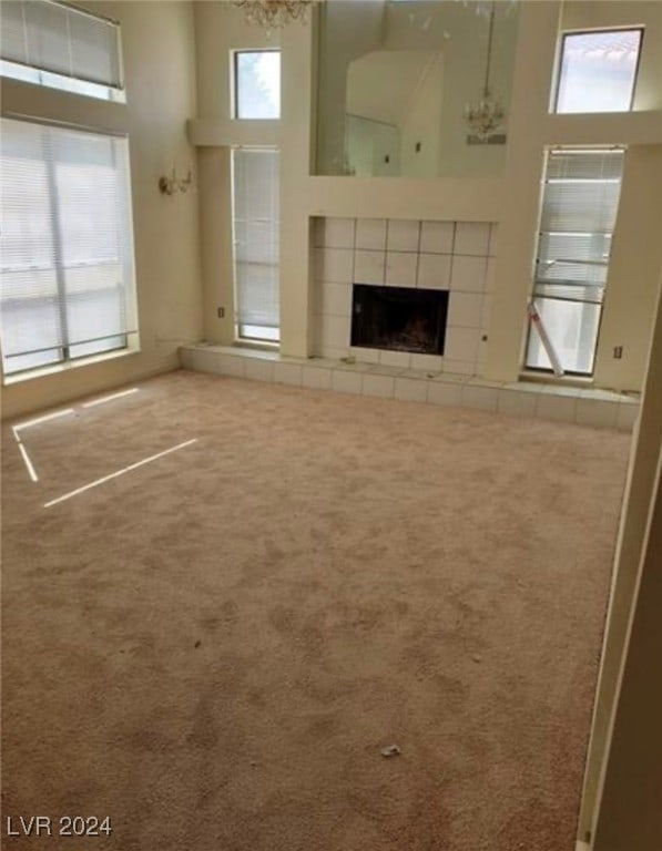 unfurnished living room featuring plenty of natural light, a high ceiling, and carpet flooring