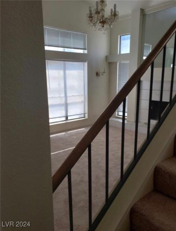 staircase with carpet flooring and an inviting chandelier